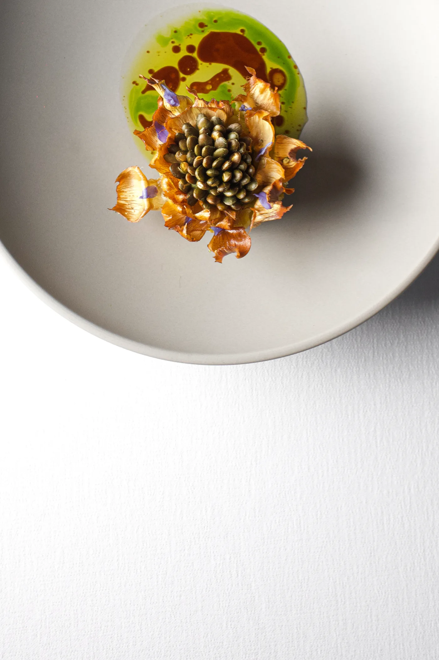 Assiette gastronomique en vue de dessus, dressage végétal et huile d'herbes