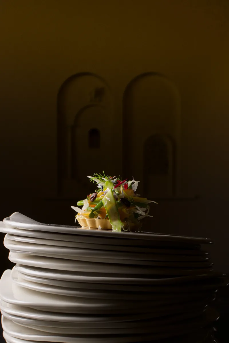 Tartelette de légumes posée sur une pile d'assiettes, lumière de clair-obscur