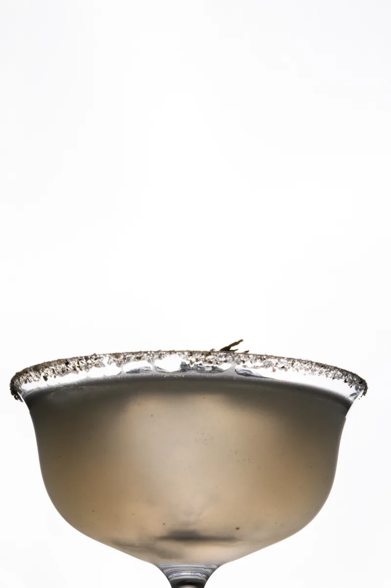 Coupe givrée au bord de sel, détail de cocktail sur fond clair