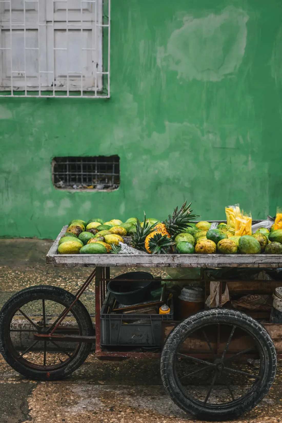 Charrette de fruits devant un mur vert, scène de rue